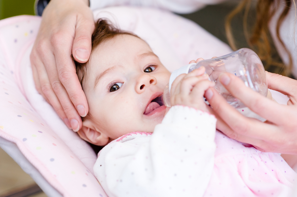 A woman gives water to her baby suffering from acute diarrhea A woman gives water to her baby suffering from acute diarrhea