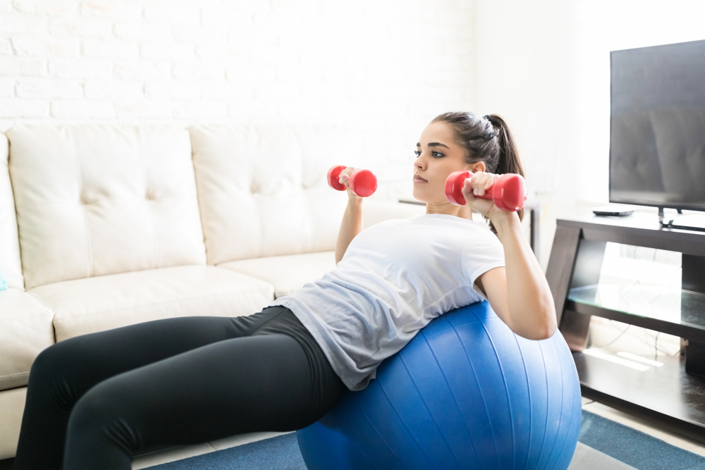 A woman doing stability ball exercises with weights A woman doing stability ball exercises with weights