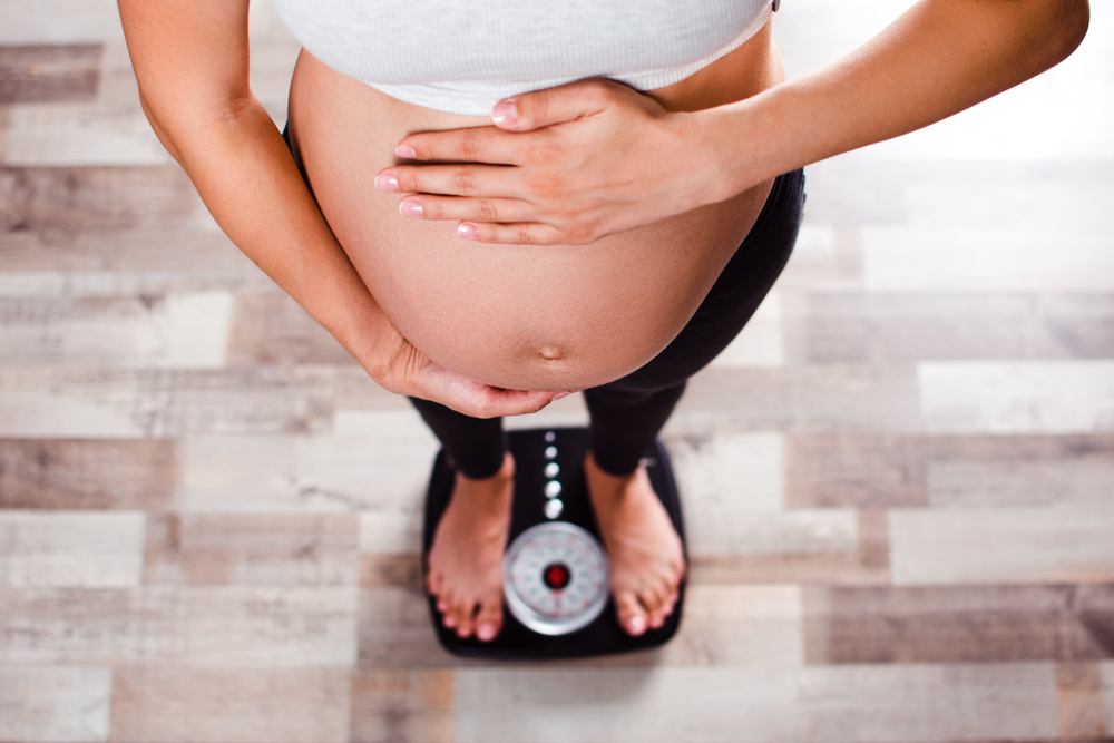 A woman pregnant with twins measures her weight A woman pregnant with twins measures her weight
