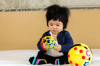 A 7-month-old baby playing with plastic balls