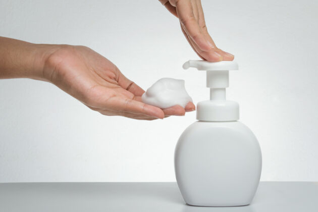 Woman presses pure white plastic pump bottle Woman presses pure white plastic pump bottle