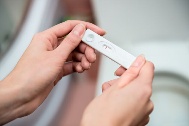 woman holding negative pregnancy test at 6 DPO